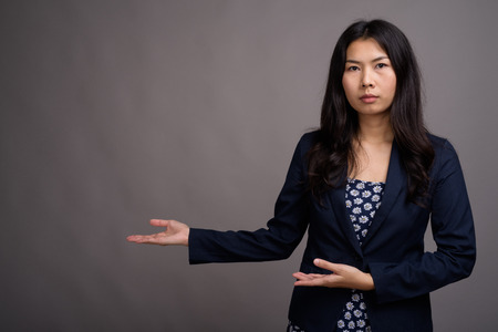 Asian woman wearing blue dress and cardigan sweater against grayの写真素材