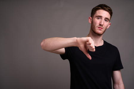 Portrait of young handsome man against gray background