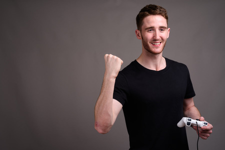 Young handsome man playing games against gray background
