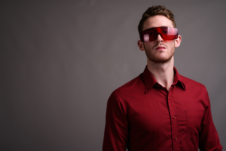 Young handsome businessman wearing red shirt against gray backgrの写真素材