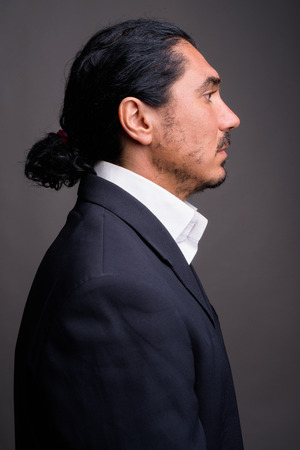 Handsome businessman with mustache wearing suit against gray bacの写真素材