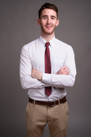 Portrait of young handsome businessman against gray backgroundの写真素材