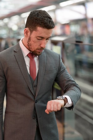 Young handsome Caucasian businessman looking watch at train statの写真素材