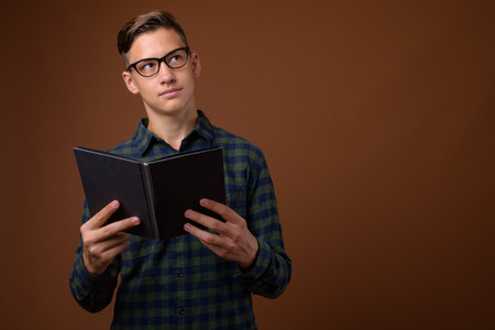 Studio shot of young handsome teenage boy against brown backgrouの写真素材