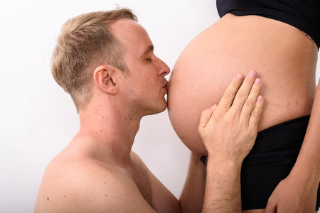 Man kissing the stomach of his pregnant wife with stomach