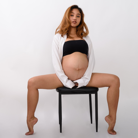 Portrait of beautiful young pregnant Asian woman sittingの写真素材