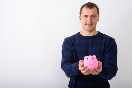 Studio shot of young happy muscular man smiling while holding piの写真素材