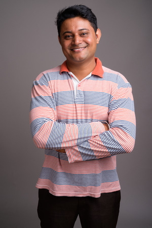 Portrait of young Indian man against gray backgroundの写真素材