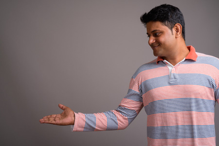 Portrait of young Indian man against gray backgroundの写真素材