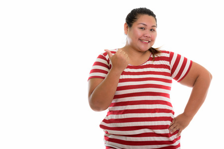 Studio shot of young happy fat Asian woman smiling and giving thの写真素材