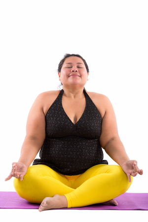 Studio shot of young fat Asian woman meditating with eyes closedの写真素材