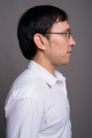 Young Asian nerd man wearing eyeglasses against gray backgroundの写真素材