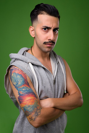 Young handsome Iranian man with mustache against green backgrounの写真素材