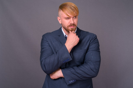 Bearded businessman with blond hair against gray backgroundの写真素材