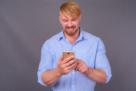 Bearded businessman with blond hair against gray backgroundの写真素材