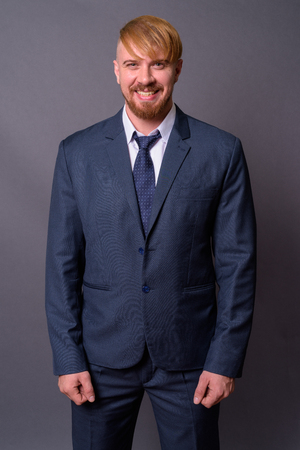 Bearded businessman with blond hair against gray backgroundの写真素材