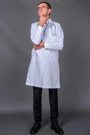 Handsome man doctor with short hair against gray backgroundの写真素材