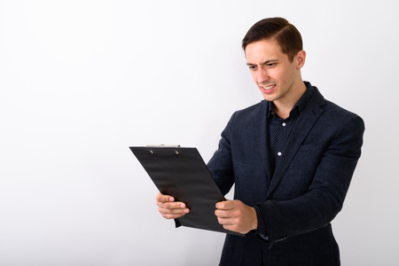 Studio shot of angry young businessman looking at clipboard agaiの写真素材