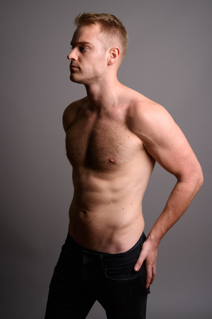 Young handsome man with blond hair shirtless against gray backgrの写真素材