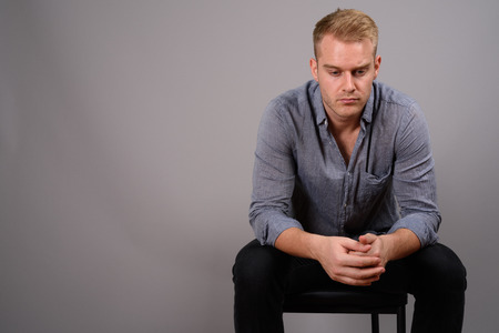 Young handsome businessman with blond hair against gray backgrouの写真素材