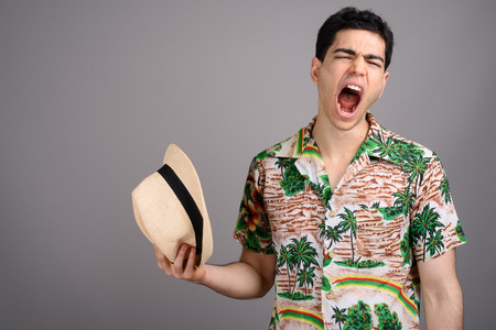 Young handsome tourist man ready for vacation against gray backgの写真素材