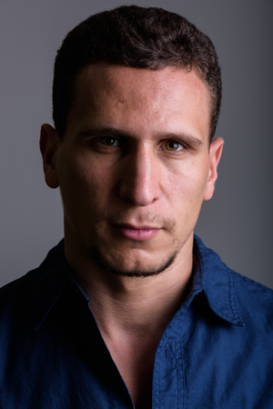 Face of young muscular Persian man against gray backgroundの写真素材