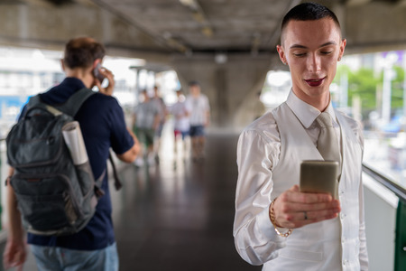 Young androgynous homosexual LGTB businessman using phoneの写真素材