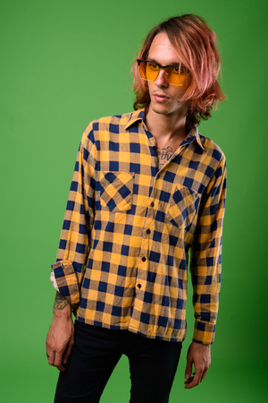 Studio shot of rebellious young man against green backgroundの写真素材