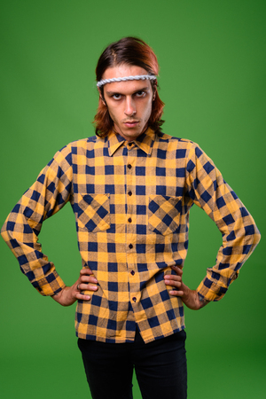 Studio shot of rebellious young man against green backgroundの写真素材