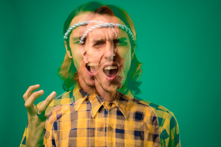 Studio shot of rebellious young man against green backgroundの写真素材