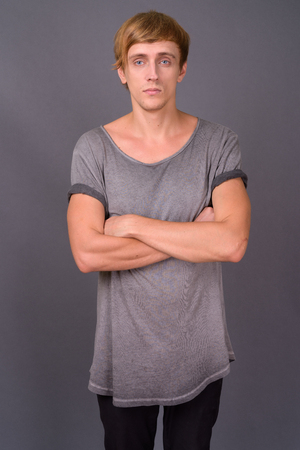 Young handsome man with blond hair against gray backgroundの写真素材