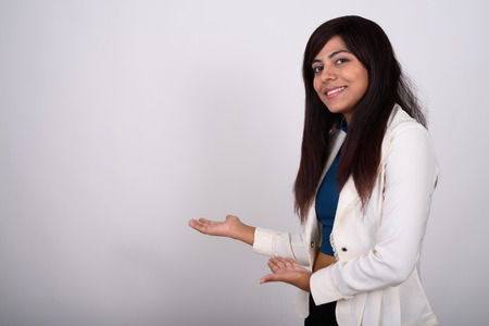 Studio shot of young happy Persian businesswoman smiling while sの写真素材