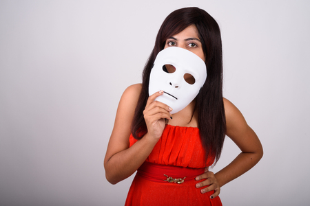 Studio shot of young Persian woman covering face with white maskの写真素材