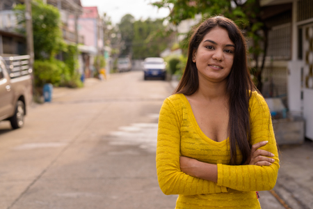 Young happy Indian woman smiling with arms crossed in the streetの写真素材