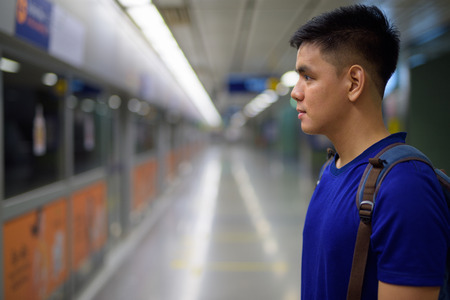 Young Asian tourist man waiting for the train at the subway stationの写真素材