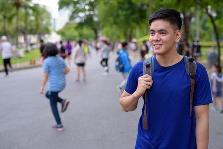 Young handsome Asian tourist man with backpack relaxing at the pの写真素材