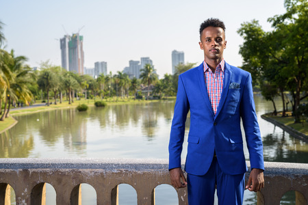 Young handsome African businessman relaxing at the park in Bangkの写真素材