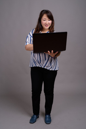 Full length portrait of Japanese businesswoman using laptop computerの写真素材