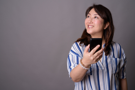 Mature beautiful Asian businesswoman using mobile phoneの写真素材