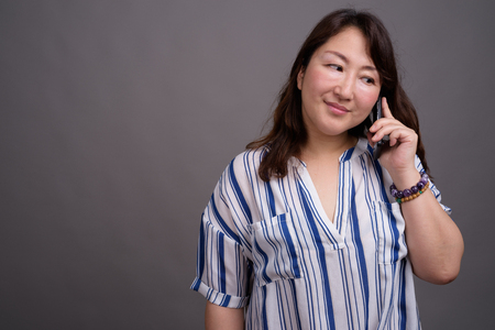 Mature beautiful Asian businesswoman talking on phoneの写真素材