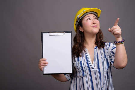 Mature Asian businesswoman construction worker wearing hardhat