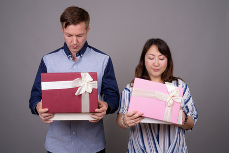 Businessman and mature Asian businesswoman holding gift boxの写真素材