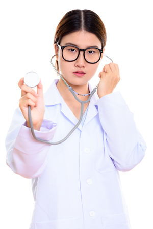 Studio shot of young beautiful Asian woman doctor using stethoscの写真素材