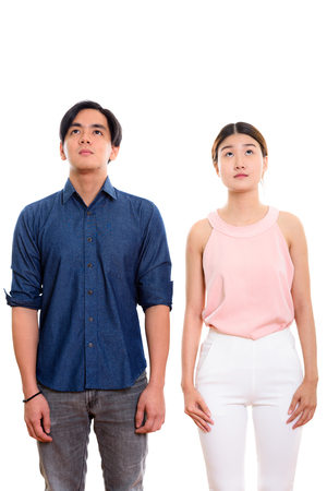 Studio shot of young Asian couple standing while looking upの写真素材
