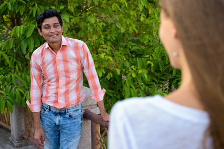 Happy Indian man smiling and looking at beautiful woman in loveの写真素材