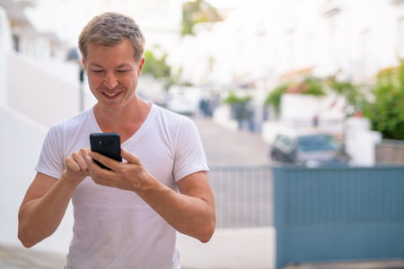 Young Happy Handsome Man Using Phone In The Streets Outdoorsの写真素材