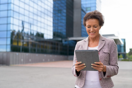 Happy Mature Businesswoman Using Digital Tablet Outdoorsの写真素材