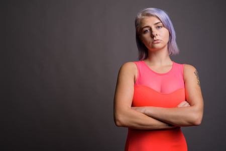 Young beautiful rebel woman with colorful hair against gray backの写真素材