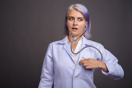 Young beautiful woman doctor with short colorful hair against grの写真素材