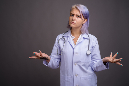 Young beautiful woman doctor with short colorful hair against grの写真素材